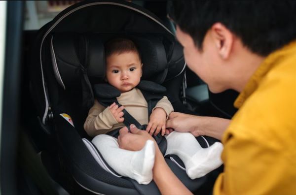 赤ちゃんをチャイルドシートに乗せる男性の写真
